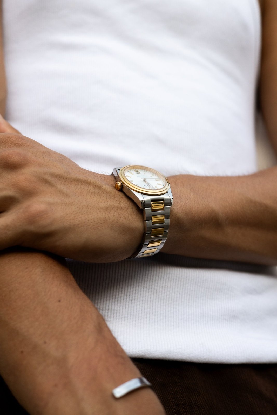 Arms crossed over a white T-shirt, watch on the wrist