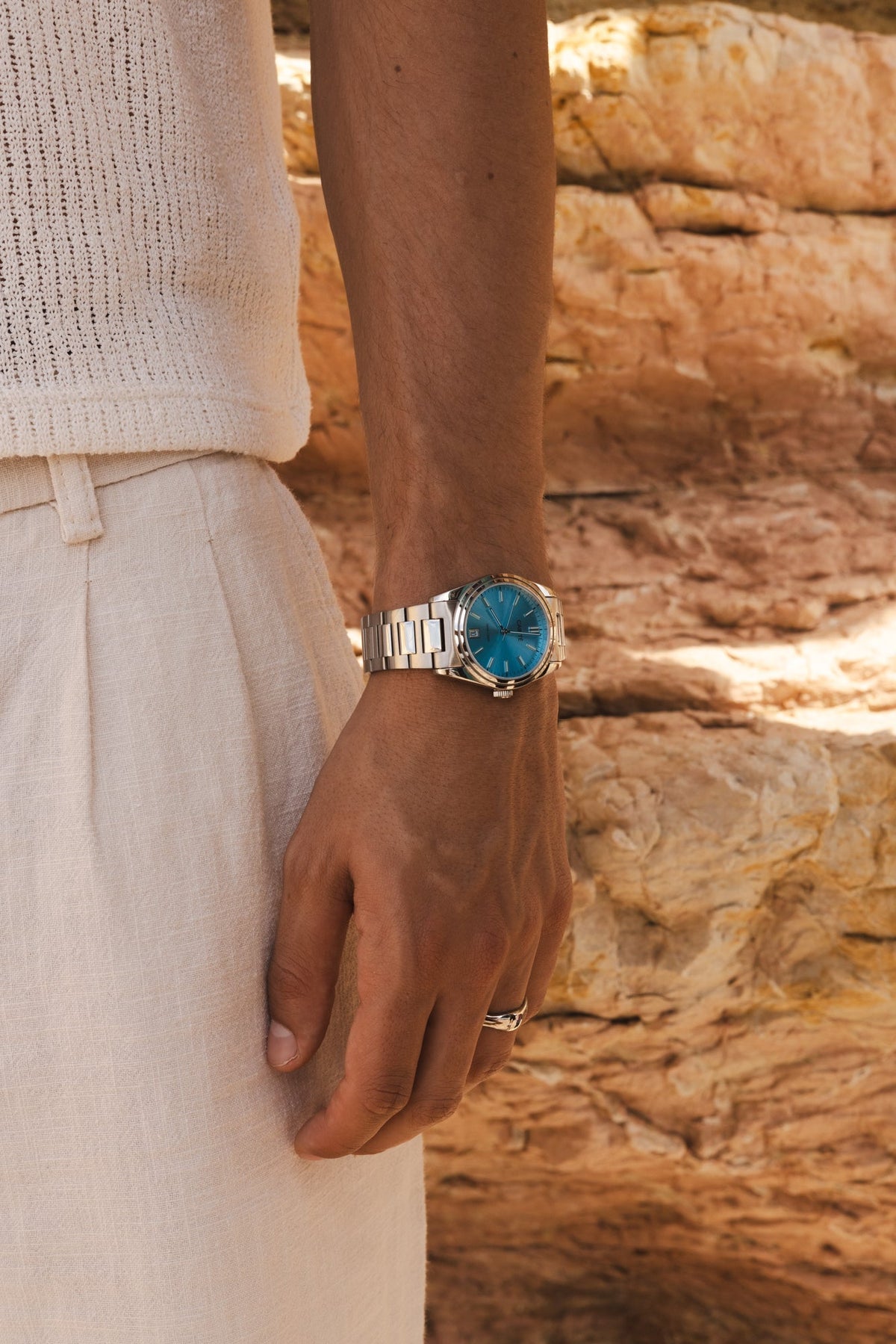 Arm by sunlit rocks with the turquoise watch on the wrist