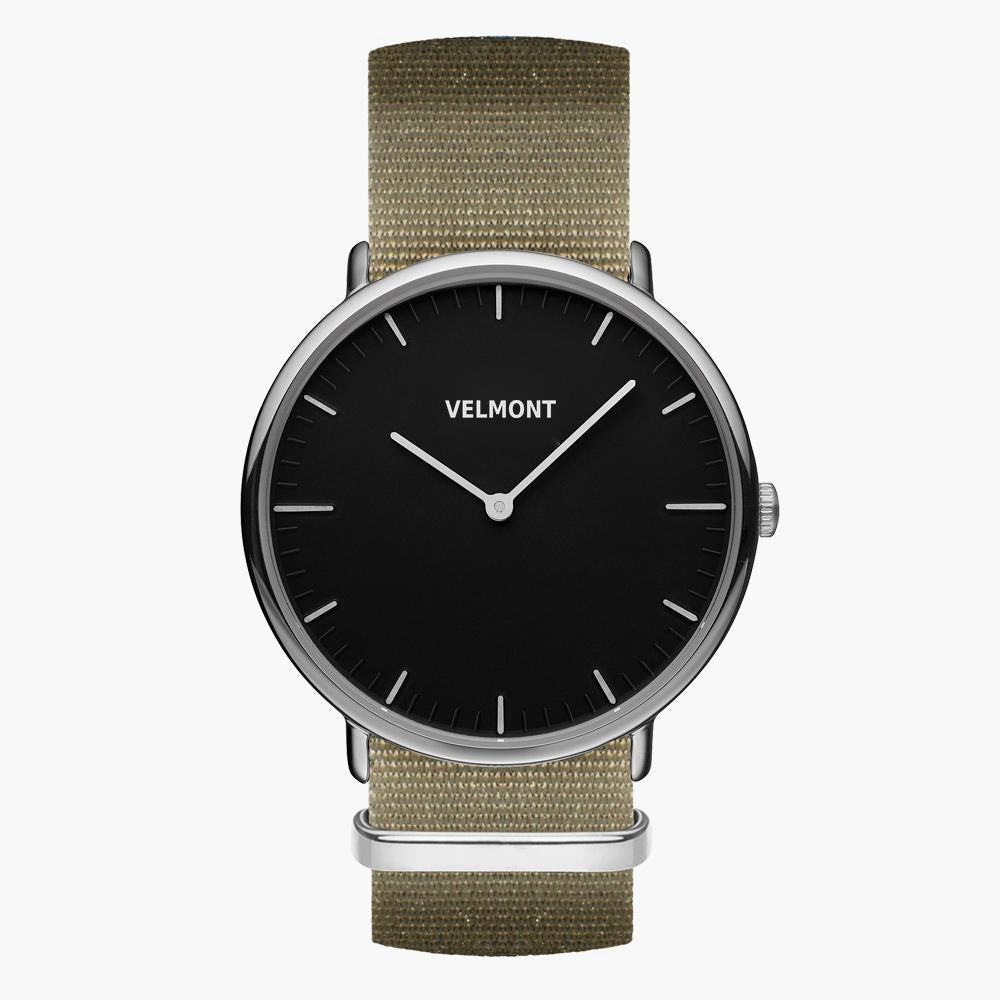 Black-dial watch with a silver-tone case on a khaki woven strap, front view.
