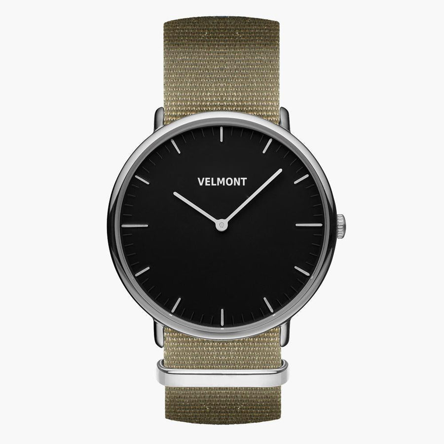 Black-dial watch with a silver-tone case on a khaki woven strap, front view.