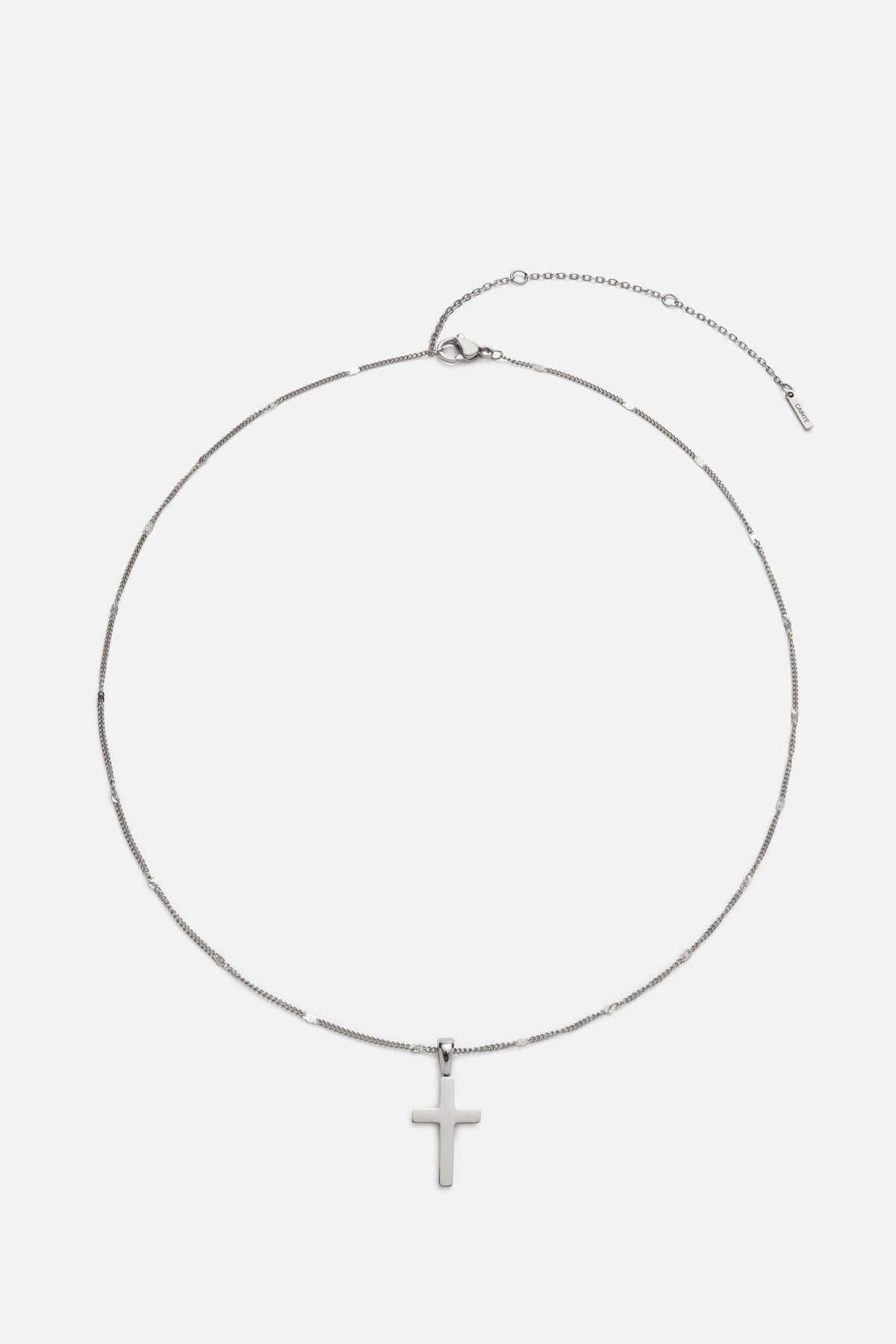 Silver-tone cross necklace laid flat with extender chain
