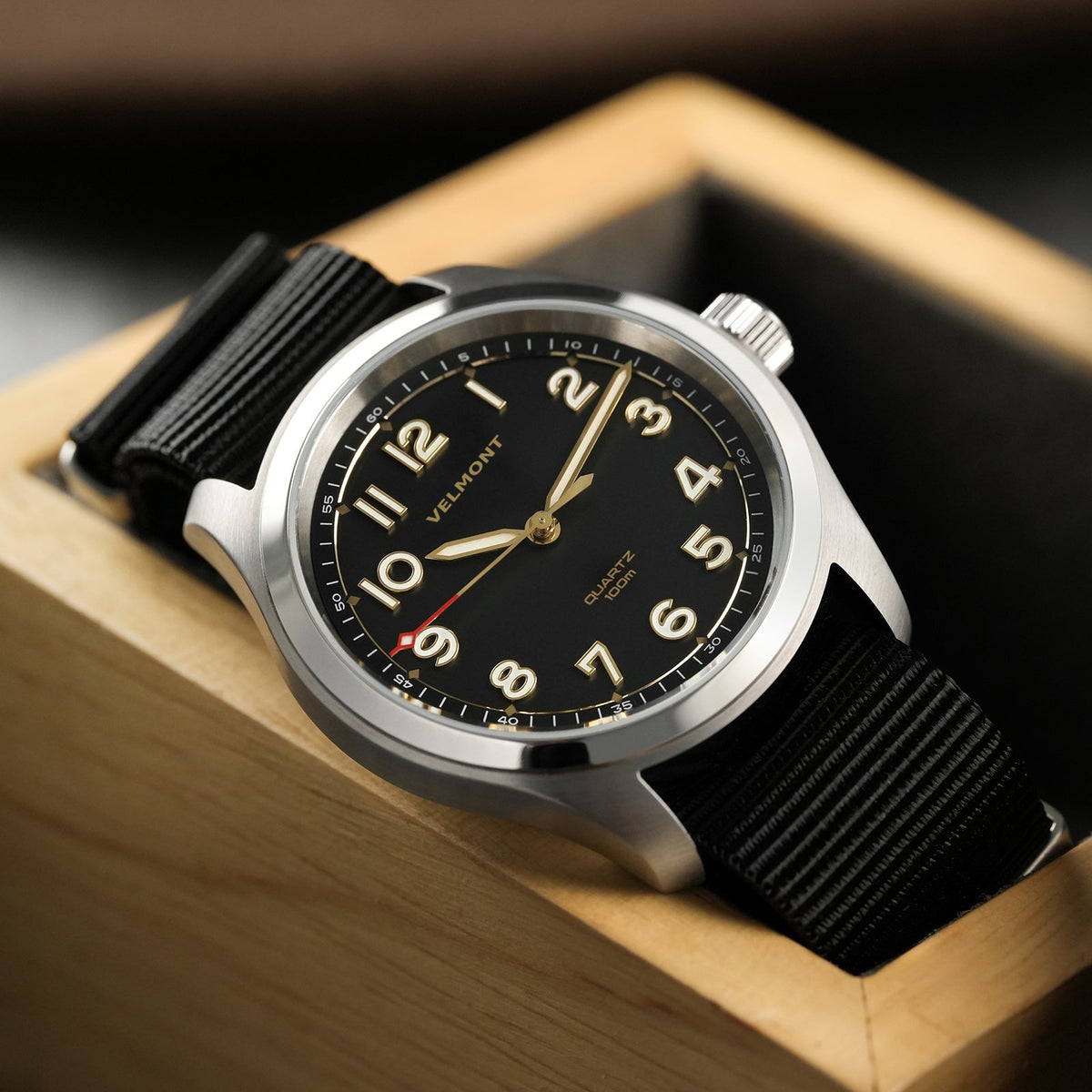 Field watch with nylon strap in an open wooden box