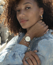 Silver-tone watch worn with a blue shirt and bracelets