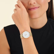 Round gold-tone watch worn near the face