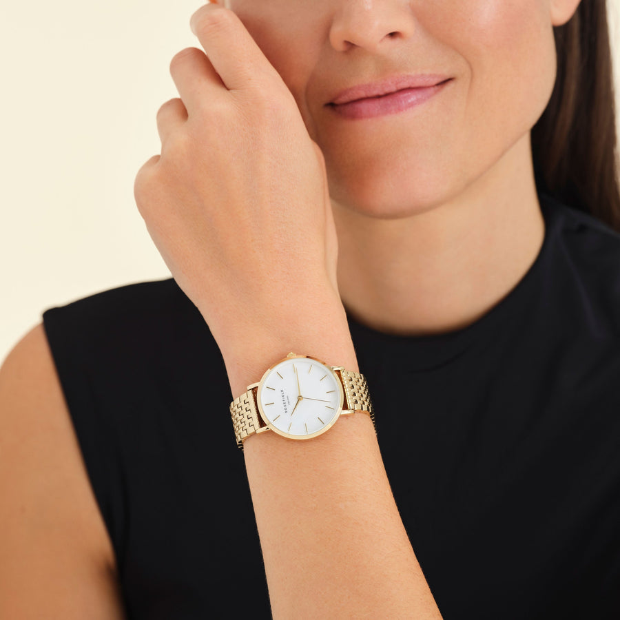 Round gold-tone watch worn near the face