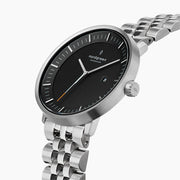 Angled view of the brushed silver-tone case, crown and black dial with date.