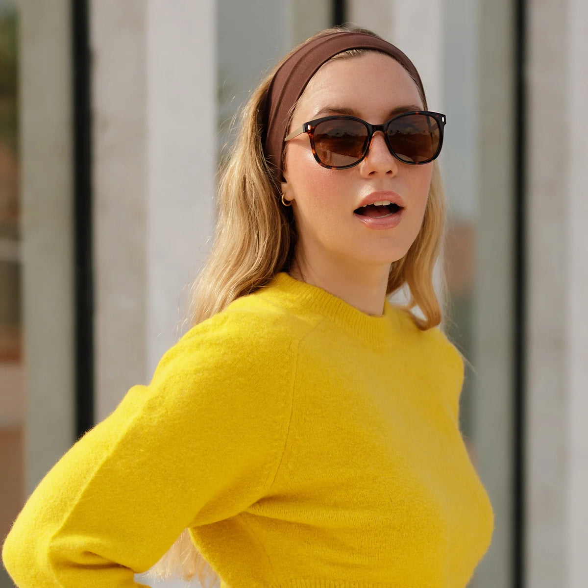 Woman in a yellow sweater wearing tortoise sunglasses