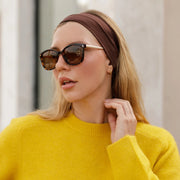 Woman touching her neck in oversized sunglasses