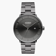 Gunmetal watch with a gray sunburst dial and date window, front view.