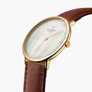 Angled view showing the iridescent sheen of the pearlescent dial and gold-tone case.