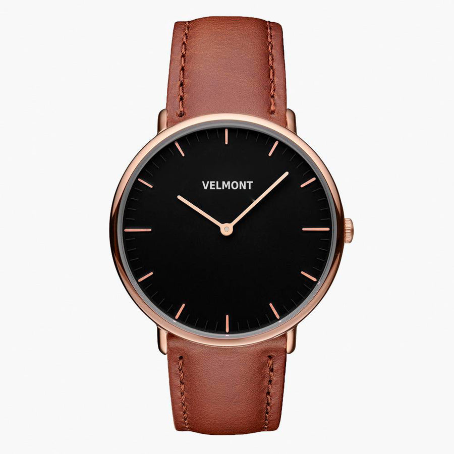 A black dial framed by a slim rose gold-tone case, set on a brown strap.