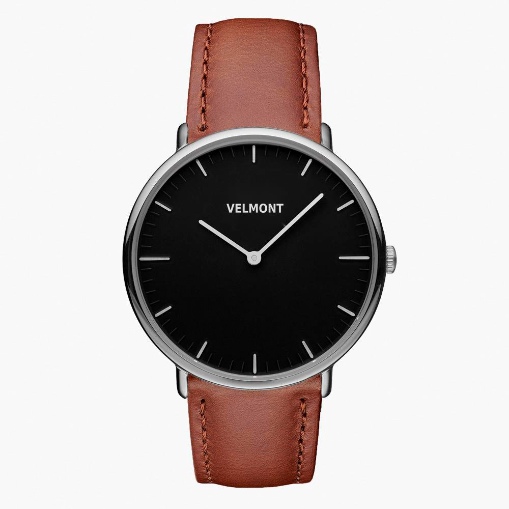 Watch with a black dial and silver-tone case on a brown strap, shown from the front.