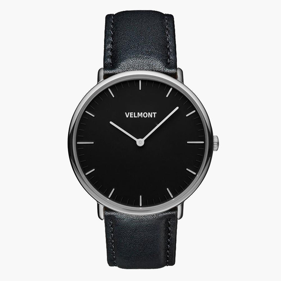 Watch with a black dial and silver-tone case on a black strap, shown from the front.