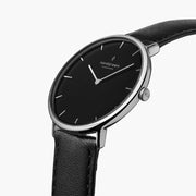 The silver-tone watch tilted to reveal its black dial and side crown.