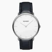 Minimal watch with a white dial and silver-tone case on a black strap, front view.