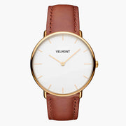 Minimalist watch with a white dial and gold-tone case on a cognac brown strap.