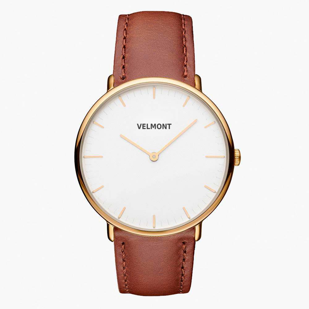 Minimalist watch with a white dial and gold-tone case on a cognac brown strap.