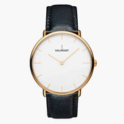 Minimalist watch with a white dial and gold-tone case on a black strap.