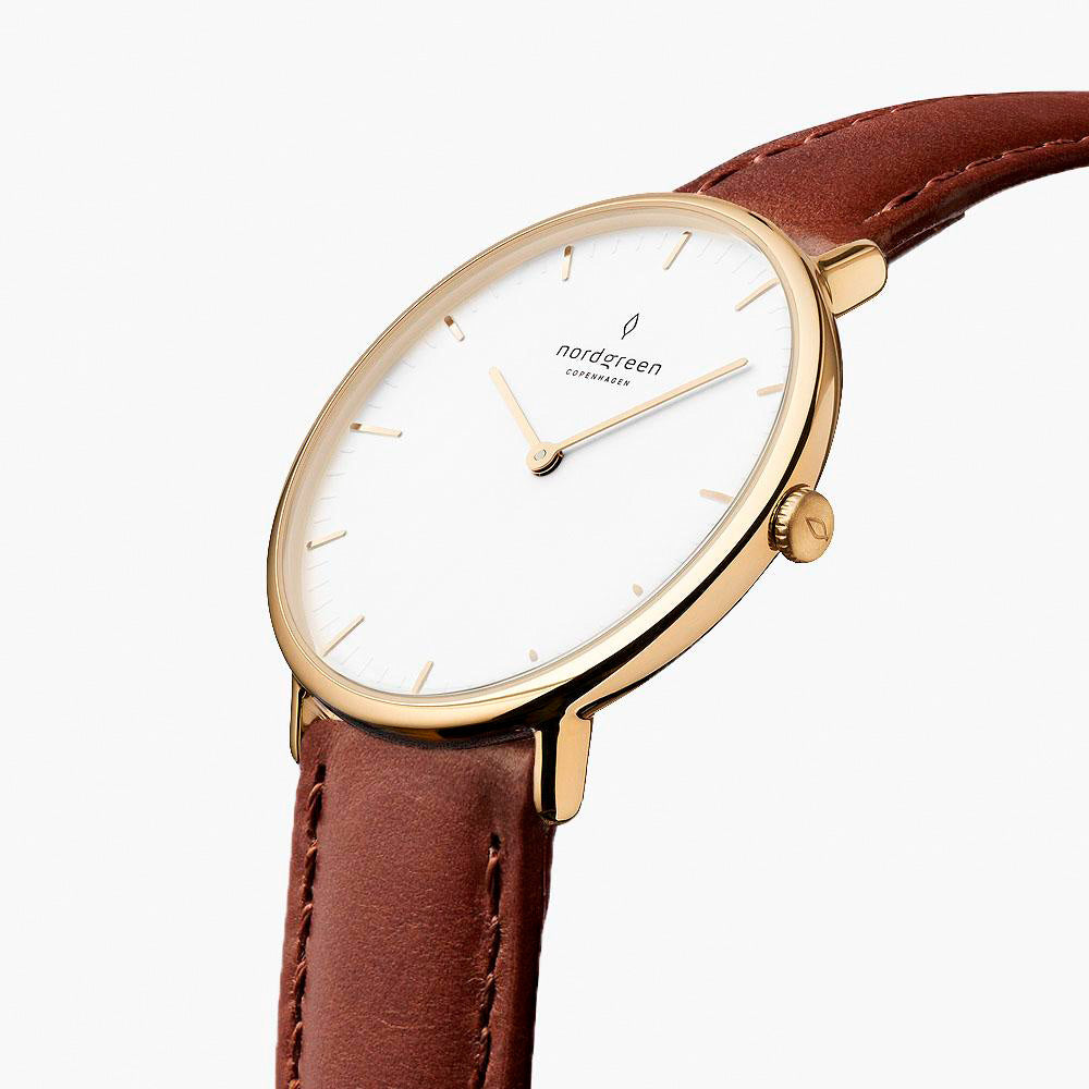 Angled view of the slim gold-tone case and crown on a brown strap.