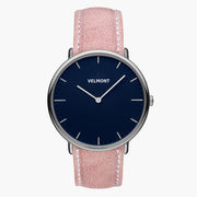 Watch with a navy blue dial and silver-tone case on a pink strap with white stitching.