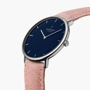 Three-quarter view of the thin silver-tone case and blue dial on a pink strap.