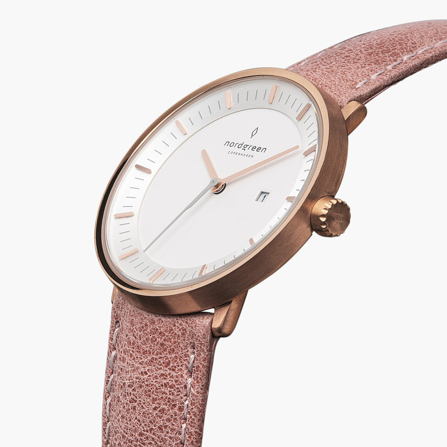 Three-quarter view of the rose gold-tone case and date window on a pink strap.