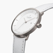 Three-quarter view of the silver-tone case and date window on a white strap.
