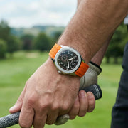 Orange-strap watch worn on a golf course