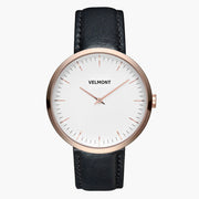 Minimalist watch with a white dial and rose gold-tone case on a black strap.