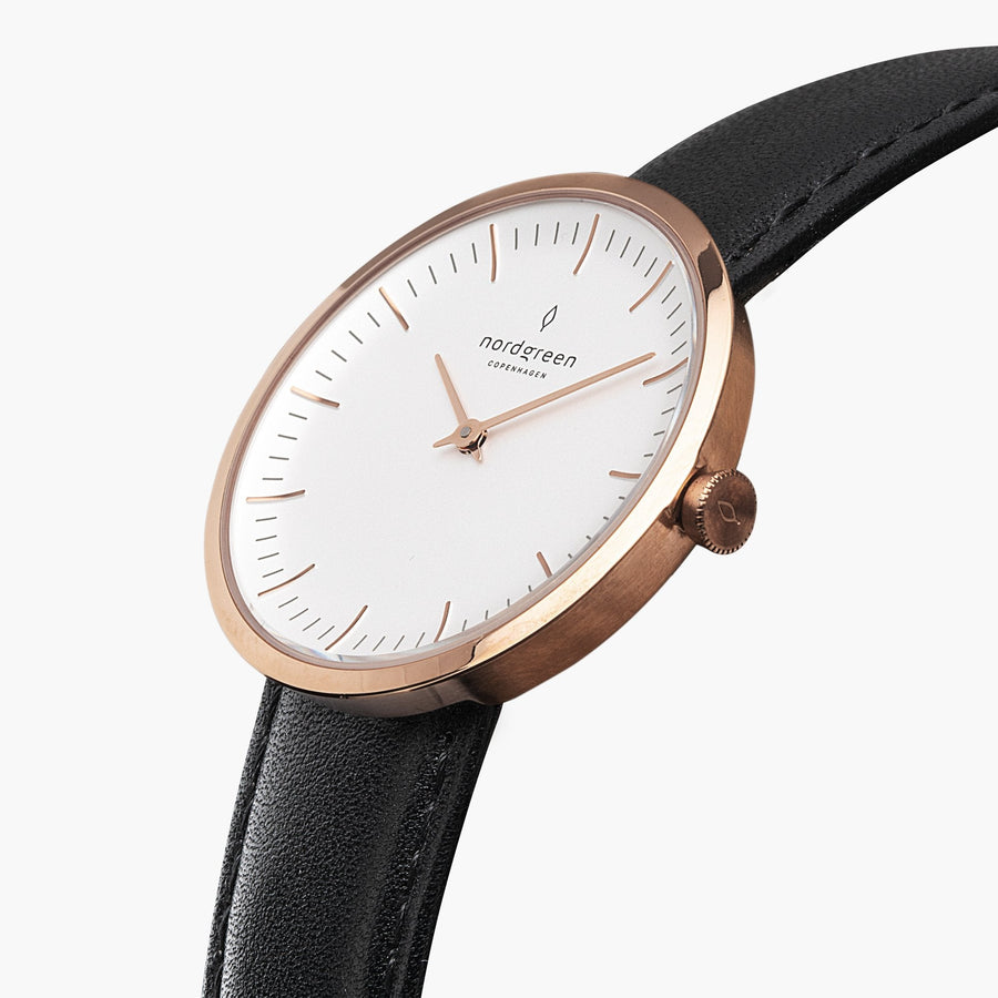 Angled view of the slim rose gold-tone case and white dial on a black strap.