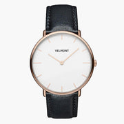 A white dial framed by a slim rose gold-tone case, set on a black strap.