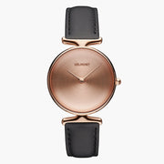 Watch with a rose gold-tone dial and case on a smooth black strap.