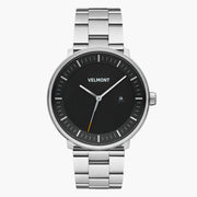 Black-dial watch with an orange-tipped seconds hand on a silver-tone bracelet.