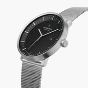 Three-quarter view of the watch showing the black dial and silver-tone mesh strap.