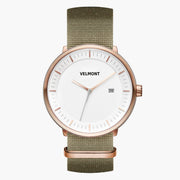 Watch with a white dial and rose gold-tone case on an olive green woven strap.