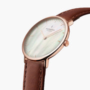 Close angle on the shimmering dial, rose gold-tone crown and brown strap.