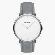 Minimalist watch with a white dial and silver-tone case on a gray strap.