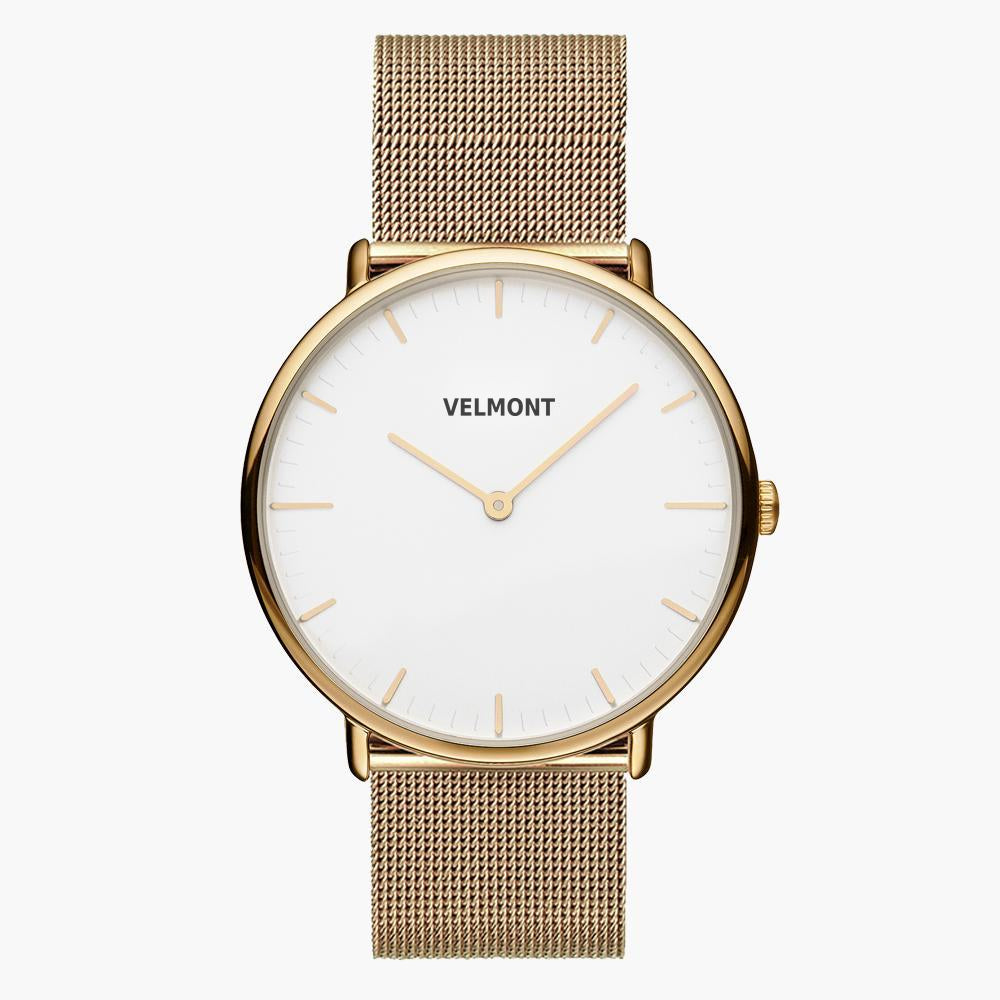 Minimalist watch with a white dial and gold-tone case on a gold-tone mesh strap.