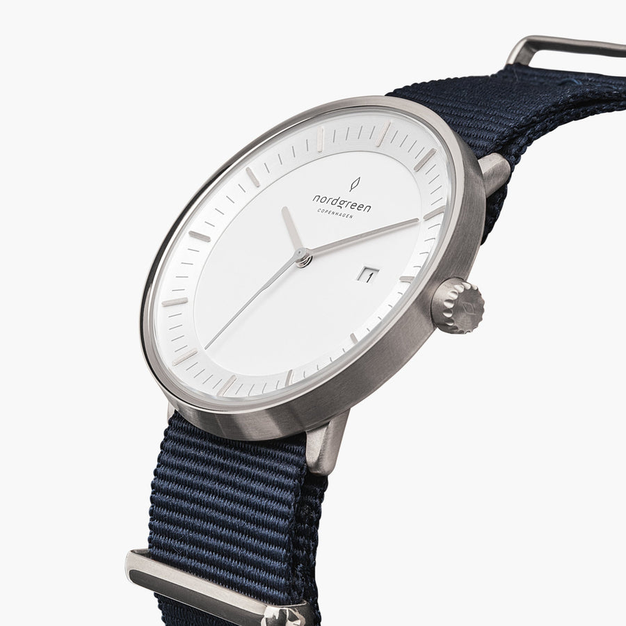 Three-quarter view of the silver-tone case and date window on a navy fabric strap.