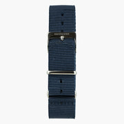 Navy ribbed nylon strap that passes under the case, with polished metal hardware.
