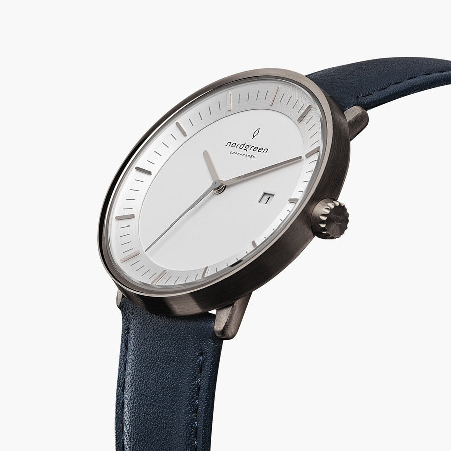 Three-quarter view of the white dial, date window and gunmetal crown on a navy strap.