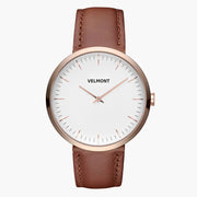 Minimalist watch with a white dial and rose gold-tone case on a caramel brown strap.