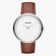 Slim watch with a white dial and silver-tone case on a brown strap.