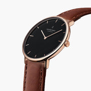 The rose gold-tone watch tilted to reveal its black dial and side crown.