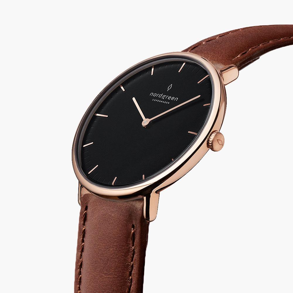 The rose gold-tone watch tilted to reveal its black dial and side crown.