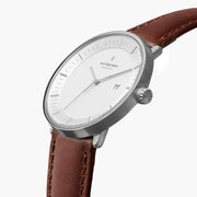 Watch turned at an angle, white dial and silver-tone bezel catching the light.