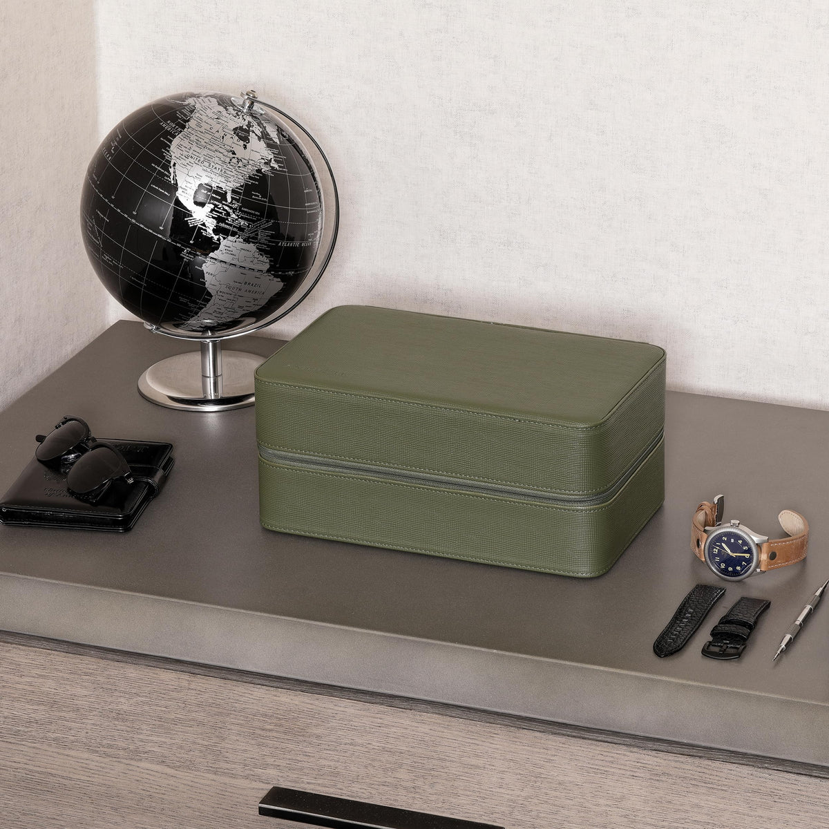 Closed green travel case on a desk next to a globe