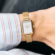 Rectangular watch with a white dial worn with a striped shirt cuff.