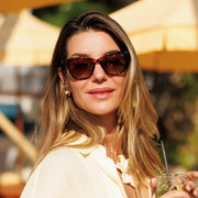 Woman in tortoise cat eye sunglasses holding a drink
