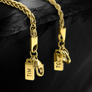 Two gold-tone clasps and tags hanging side by side